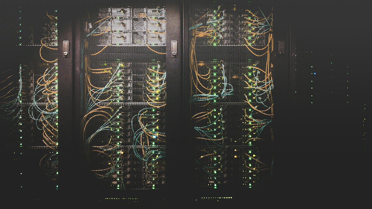 Rack di server con luci verdi lampeggianti e cavi colorati.